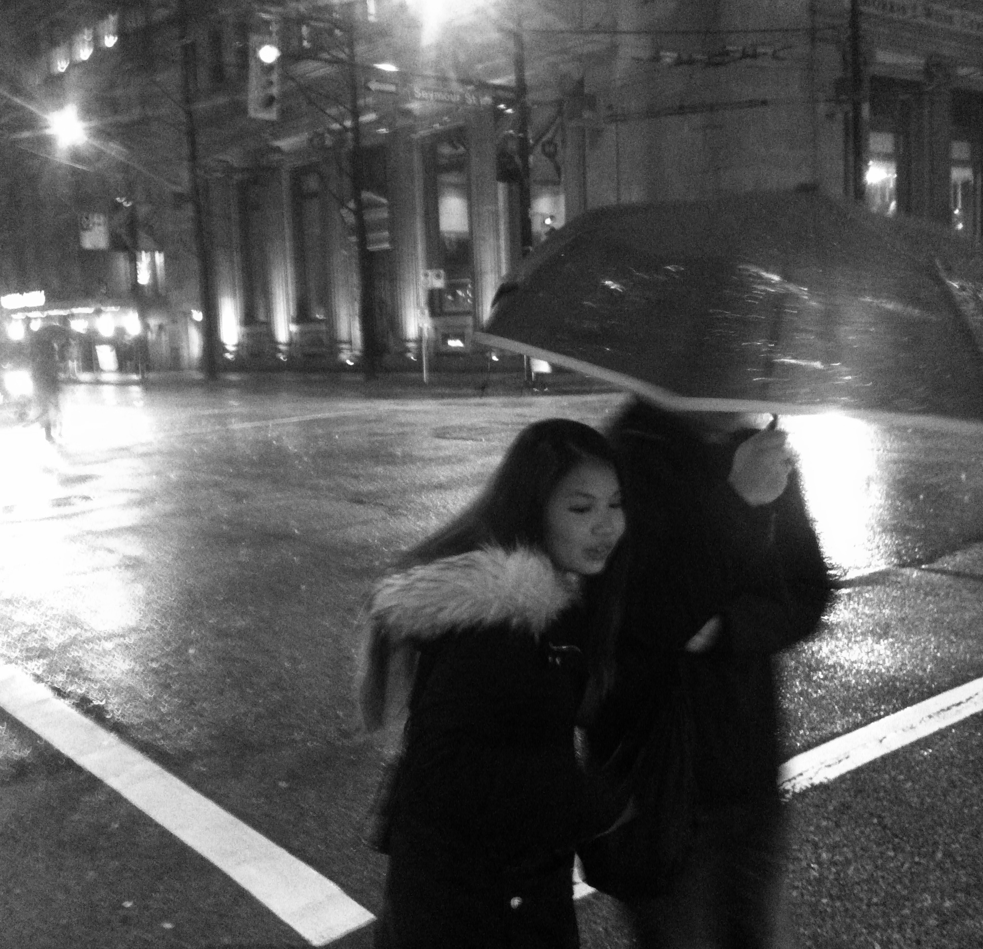 Man and woman under umbrella on wet city street at night