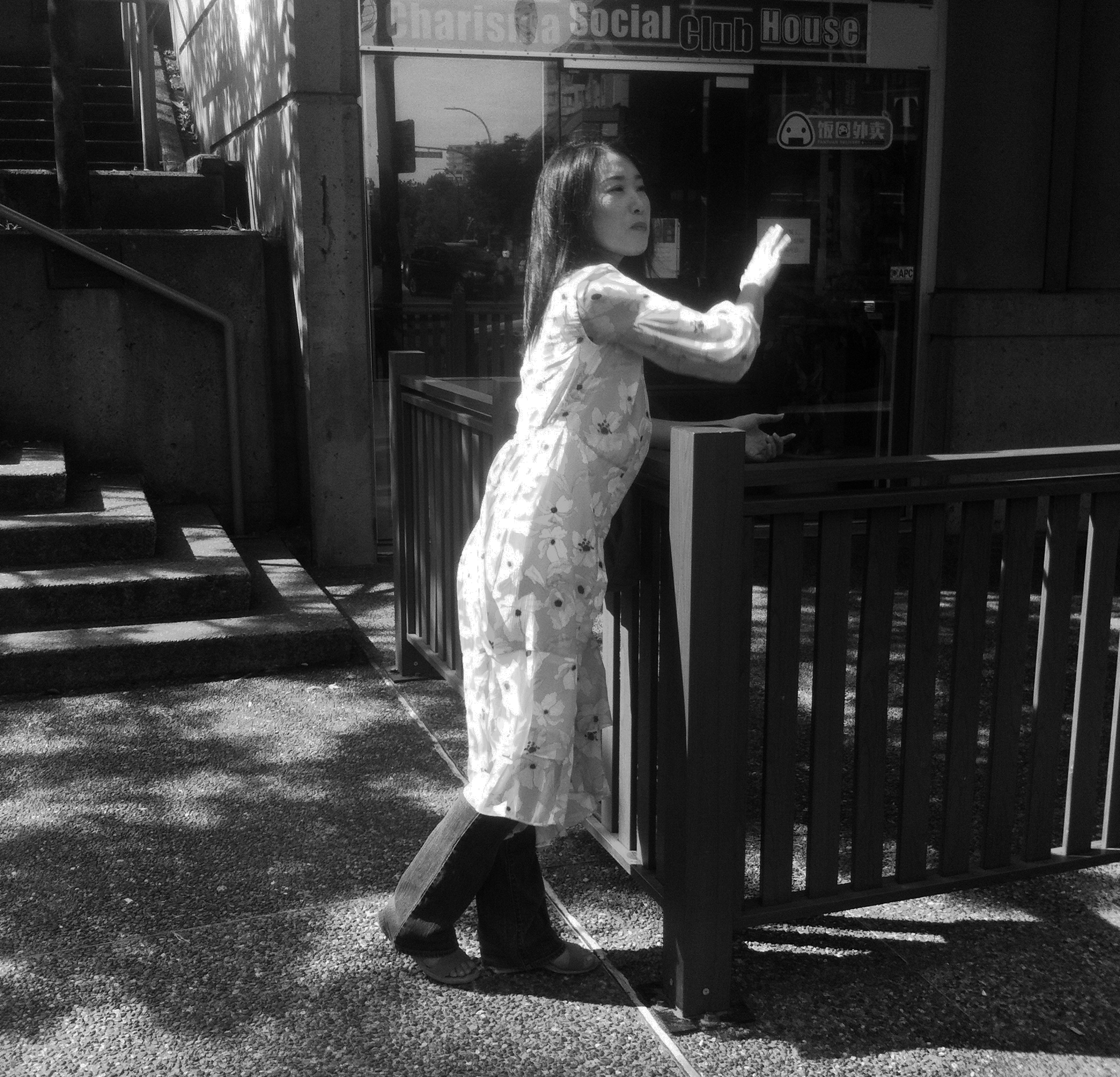 Woman in white dress against dark railing and storefront